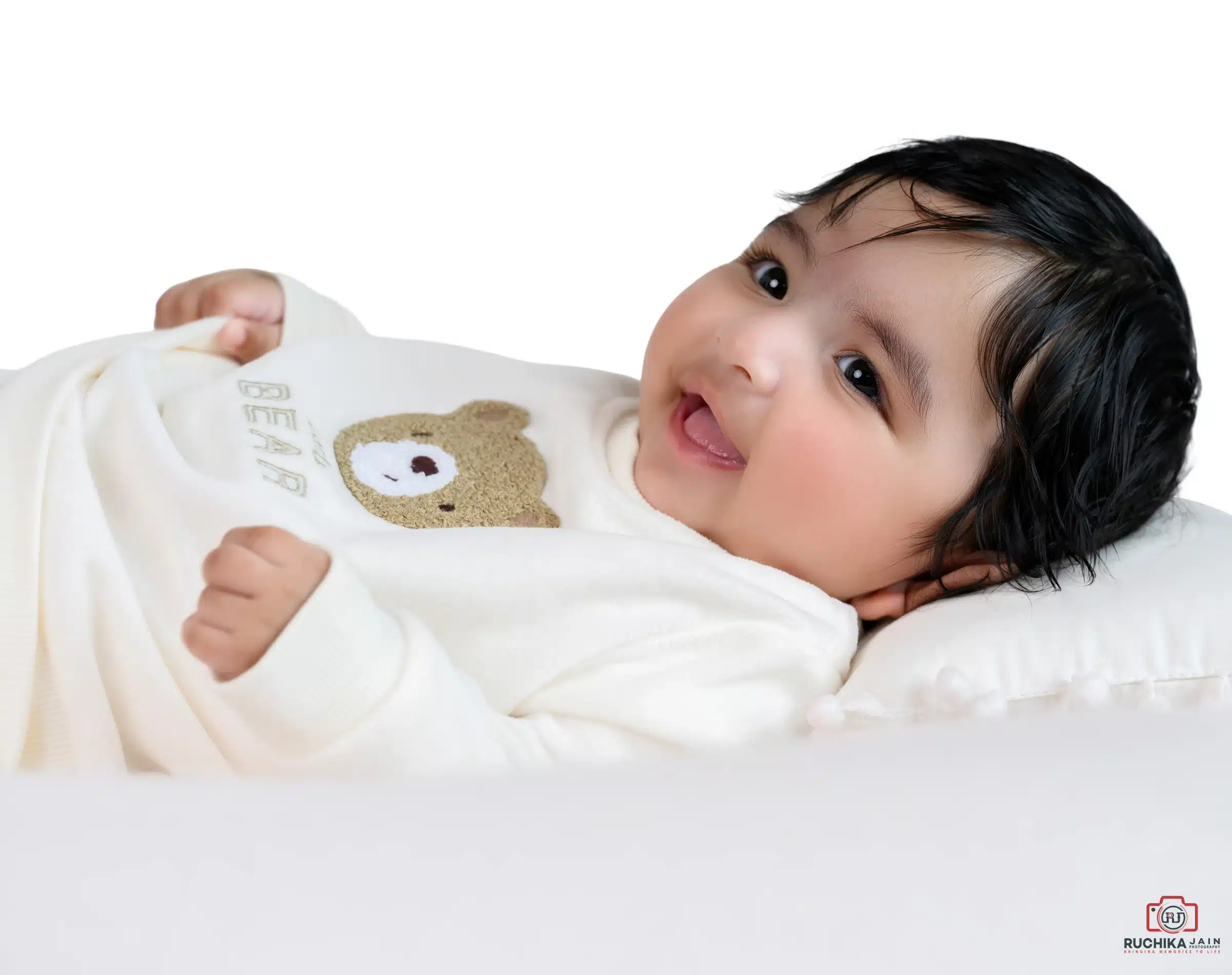 Adorable baby smiling while lying on a pillow during a professional family photoshoot in Wellington